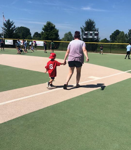 mom and child walk on baseball field